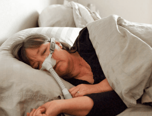 A Canadian woman in bed using a CPAP machine for her sleep apnea. 