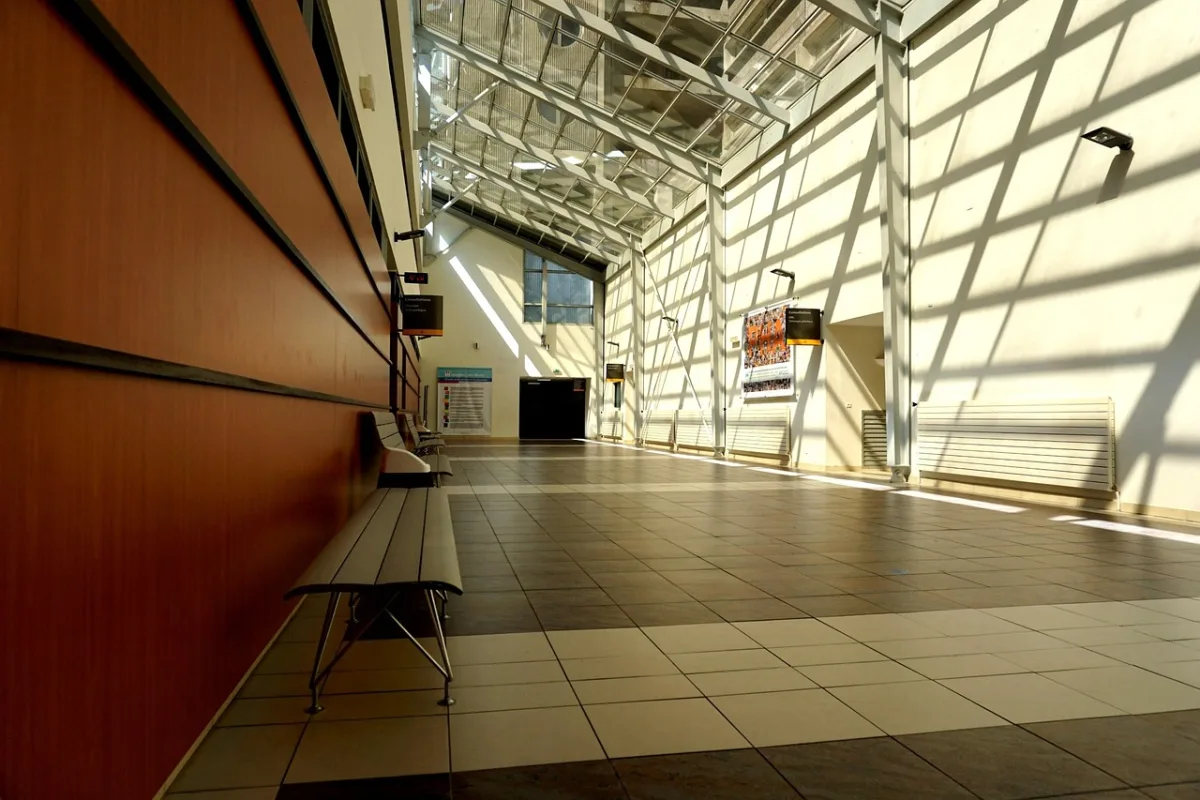 A bright, empty hospital corridor with benches and daylight.