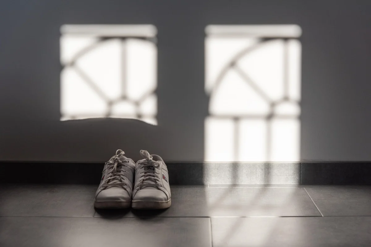 A pair of trainers on a floor in window light.