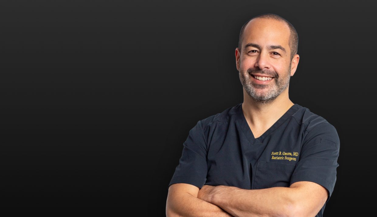 Smiling bariatric surgeon at Sleeve Clinic with arms crossed, conveying expertise and approachability.